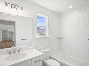 Full bathroom with vanity, hardwood / wood-style flooring, toilet, and tiled shower / bath combo