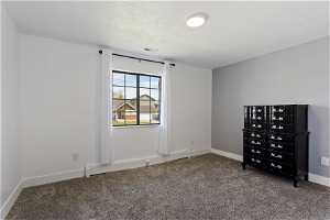Unfurnished bedroom featuring a textured ceiling, baseboard heating, and carpet flooring