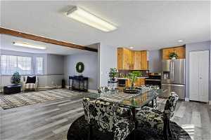 Dining space with light hardwood / wood-style flooring, beam ceiling, and a textured ceiling