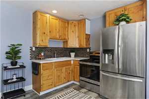 Kitchen featuring a textured ceiling, sink, backsplash, stainless steel appliances, and hardwood / wood-style flooring