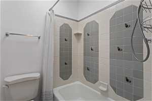 Bathroom featuring toilet and shower / bath combo with shower curtain