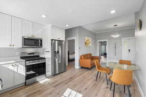 Kitchen featuring appliances with stainless steel finishes, hanging light fixtures, and white cabinets