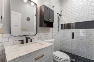 Bathroom featuring tiled shower, tile walls, large vanity