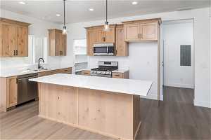 Kitchen with sink, stainless steel appliances, hardwood / wood-style floors, and a kitchen island