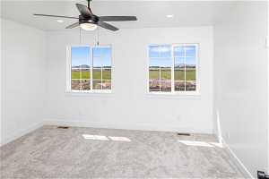 Carpeted empty room with plenty of natural light and ceiling fan