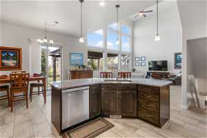 Kitchen featuring decorative light fixtures, sink, dishwasher, and a kitchen island with sink