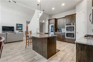 Kitchen featuring dark brown cabinetry, tasteful backsplash, stainless steel appliances, and light stone counters