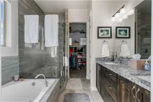 Bathroom featuring dual sinks, shower with separate bathtub, and oversized vanity