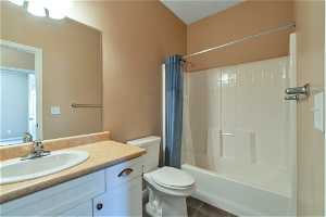 Full bathroom featuring vanity with extensive cabinet space, shower / bathtub combination with curtain, toilet, and tile flooring