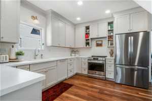 Updated kitchen featuring stainless steel appliances, LVP flooring, quartz countertops, white cabinets, and large sink