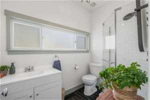 Bathroom featuring a shower with door, vanity with cabinet space, toilet, and new tile flooring