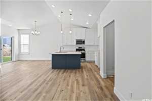 Kitchen with appliances with stainless steel finishes, a center island with sink, light hardwood / wood-style floors, white cabinets, and sink