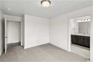 Unfurnished bedroom with light colored carpet, sink, and ensuite bath