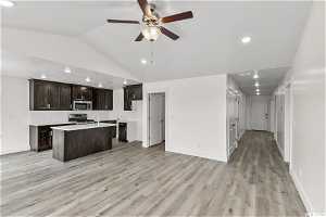 Kitchen featuring light wood-type flooring, ceiling fan, gas range, and an island with sink