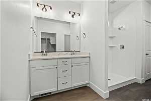 Bathroom featuring tile flooring, dual sinks, a shower, and vanity with extensive cabinet space