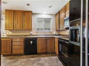 Kitchen with tile floors, high end refrigerator, sink, range with electric stovetop, and dishwasher