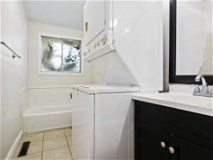 Laundry room with light tile flooring, sink, and stacked washer and clothes dryer