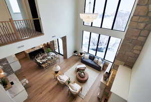 Living room featuring a towering ceiling, an inviting chandelier, and wood-type flooring