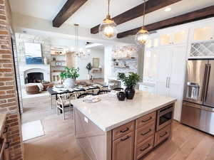 Kitchen featuring hanging light fixtures, appliances with stainless steel finishes, white cabinetry, light wood-type flooring, and a center island