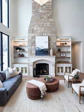 Living room with built in shelves, a high ceiling, wood-type flooring, and a large fireplace