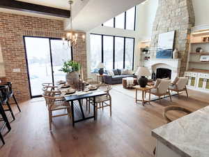 Dining room with hardwood / wood-style flooring, a healthy amount of sunlight, a towering ceiling, and an inviting chandelier