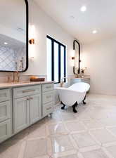 Bathroom with vanity, a bathtub, and decorative backsplash