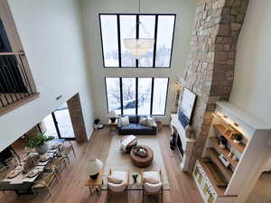 Living room featuring a chandelier, a high ceiling, a stone fireplace, and light hardwood / wood-style floors