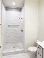 Bathroom featuring vanity, toilet, and a tile shower