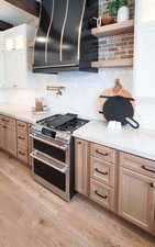 Kitchen with white cabinets, light wood-type flooring, and double oven range