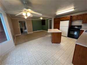 Kitchen with ceiling fan, light tile floors, white refrigerator, stove, and ornamental molding