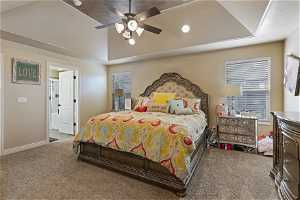 Carpeted bedroom with ensuite bath, a textured ceiling, ceiling fan, and a tray ceiling