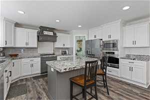Kitchen featuring premium range hood, dark hardwood / wood-style floors, a kitchen island, and stainless steel appliances