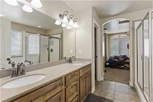Bathroom with an enclosed shower, tile floors, vanity with extensive cabinet space, and double sink