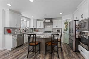 Kitchen featuring a kitchen island, appliances with stainless steel finishes, custom range hood, and dark hardwood / wood-style floors