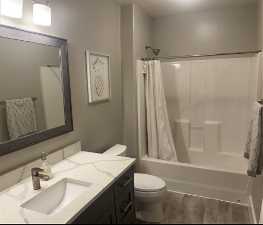 Full bathroom with hardwood / wood-style floors, large vanity, toilet, and shower / bath combo with shower curtain
