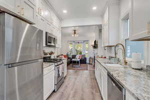 This gorgeous kitchen features ceiling height cabinets, gold hardware, granite countertops and a large farmhouse sink