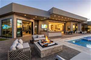 Back of property featuring a patio area and an outdoor living space with a fire pit
