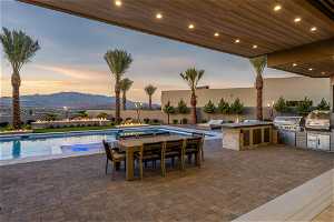 Exterior space with a fenced in pool, a mountain view, an outdoor kitchen, and grilling area