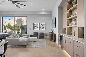 Living room featuring light hardwood / wood-style floors, ceiling fan, sink, and beverage cooler
