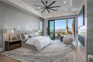 Bedroom featuring a tray ceiling, light hardwood / wood-style floors, and access to exterior