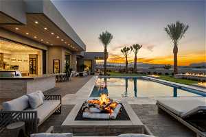 Pool at dusk featuring an outdoor living space with a fire pit and a patio