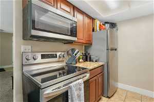 Kitchen featuring light colored carpet, stainless steel appliances, and light stone countertops