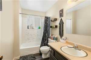 Full bathroom with shower / tub combo with curtain, hardwood / wood-style floors, vanity, and toilet
