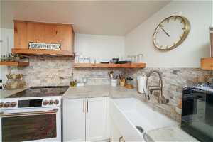 Kitchen featuring backsplash, double oven range, white cabinetry, and sink