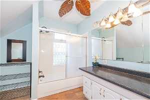 Bathroom featuring hardwood / wood-style flooring, shower / bath combination with glass door, and vanity