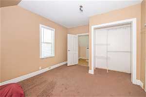 Unfurnished bedroom featuring carpet flooring, a closet, and lofted ceiling