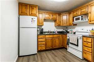 basement  Kitchen with sink, white appliances, hardwood / wood-style flooring,