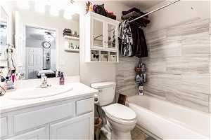 Full bathroom primary featuring tiled shower / bath, toilet, tile floors, and vanity