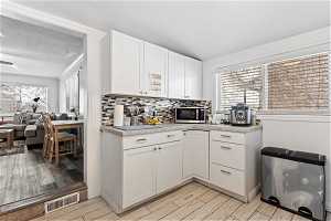 Kitchen featuring white cabinets, light hardwood / wood-style flooring, and backsplash