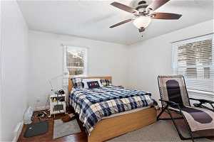 Bedroom with hardwood / wood-style floors, ceiling fan, and a textured ceiling